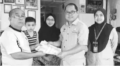  ??  ?? Dundang (second right) presents the cheque to Sapiee, witnessed by Rahani (centre) and Asmawati (right).
