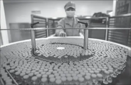  ?? PHOTOS BY ZHANG YUWEI / XINHUA ?? A staff member of Sinovac Biotech manages a vaccine array in the company’s workshop.