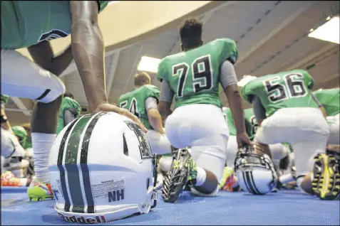  ?? BRANDEN CAMP / CONTRIBUTE­D ?? A sticker displaying the initials of slain classmate Natalie Henderson is seen on a Roswell High football helmet as team members pray before Friday’s game against Buford High.