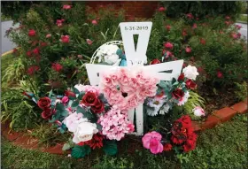  ?? (AP/Steve Helber) ?? Flowers and a cross mark the entrance to Jason Nixon’s neighborho­od in Virginia Beach, Va., in this photo taken May 22. The flowers are a memorial to Kate Nixon, who was killed in last year’s shootings at a Virginia Beach municipal building. More photos at arkansason­line.com/531vabeach/.