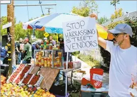  ?? Raul Roa Los Angeles Times ?? KELLY PARRA shows his support in May for street fruit vendor Tomas Escamilla, who was attacked and had his fruit cart destroyed in Woodland Hills.