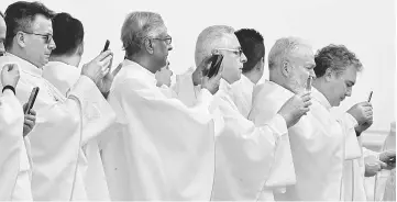  ??  ?? Clergy members use mobile phones as Pope Francis arrives to leads a holy mass at Enrique Olaya Herrera airport in Medellin, Colombia. — Reuters photo