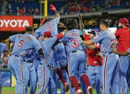  ?? HUNTER MARTIN / GETTY IMAGES ?? Phillies third baseman Maikel Franco is mobbed by teammates after he hit a walk-off three-run home run against the Marlins on Thursday.