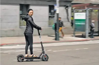  ?? Photos by Michael Macor / The Chronicle ?? A rider cruises down Mission Street on a Bird scooter. Almost no city regulation­s govern the vehicles — yet.