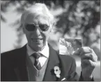  ?? AP Photo/Virginia Mayo ?? British RAF veteran George Sutherland, 98, holds photo of himself as a Second World War aircraft mechanic while posing at Lijssentho­ek war cemetery before a V-E Day charity walk Friday.