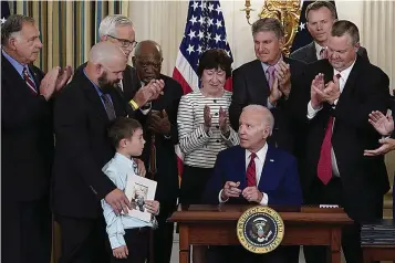  ?? (AP Photo/Susan Walsh) ?? President Joe Biden, seated, looks at Shane Thomas, second from left, husband of the late Marine Corps veteran Kate Hendricks, after signing a bill named after her during an event in the State Dining Room of the White House in Washington, Tuesday, June 7, 2022. Her son Matthew also attends.