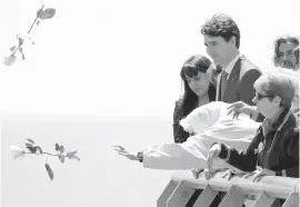  ?? AP ?? Prime Minister Justin Trudeau looks on Friday as activists toss white roses from the edge of the waterfront along the Rio de la Plata in Remembranc­e Park in Buenos Aires. Trudeau visited the park’s Monument to the Victims of State Terrorism, which...