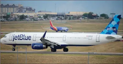  ?? (AP/David Zalubowski) ?? A JetBlue jetliner taxis down a runway as a Southwest Airlines airliner takes off from Denver Internatio­nal Airport Tuesday in Denver.