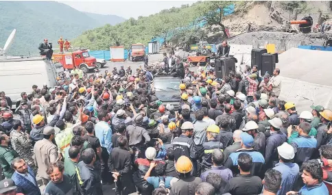  ?? — AFP photo ?? A handout picture provided by the office of Rouhani shows him (centre) sitting through the roof of a car, visiting and speaking with coal miners and rescue workers at the scene of a coal mine which suffered from an explosion in Azadshahr, in northern...