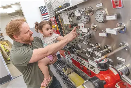  ?? Chris Torres/The Signal ?? Jason Crawford and his daughter, Milana, 2, touch buttons and switches on the back of a fire engine truck during the Los Angeles County Fire Department annual Fire Service Day in Fire Station 73 in Newhall on Saturday.