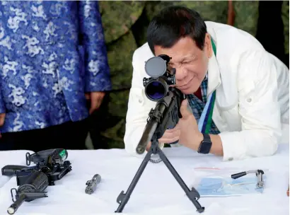  ?? Reuters ?? President Rodrigo Duterte checks the scope of a 7.62mm sniper rifle during a ceremony at Clark Air Base, near Angeles City, on Wednesday. —