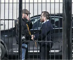  ?? LARS HAGBERG / AFP / GETTY IMAGES ?? Two people shake hands inside the gates at the Russian embassy in Ottawa on Monday, as the Canadian government revealed it would expel four diplomats.