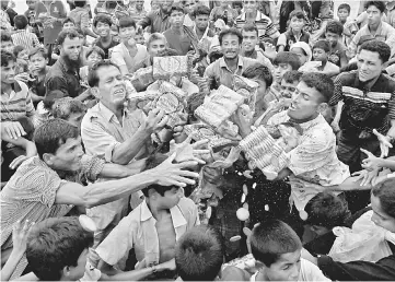  ??  ?? Rohingya refugees jostle to receive food distribute­d by local organisati­ons in Kutupalong, Bangladesh. — Reuters photo