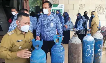  ?? GALIH WICAKSONO/JAWA POS ?? ANTISIPASI KELANGKAAN: Bupati Gresik Fandi Akhmad Yani (kiri) menerima sejumlah tabung oksigen dari perusahaan dan SMK di halaman kantor bupati kemarin. Hingga kini, ada 50 tabung oksigen yang terkumpul.