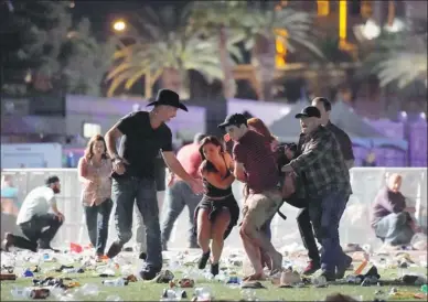  ?? DAVID BECKER / GETTY IMAGES VIA AFP ?? People carry an injured person at the Route 91 Harvest country music festival after gunfire was heard on Sunday in Las Vegas. A gunman opened fire on the music festival, killing 50 people and injuring hundreds more.