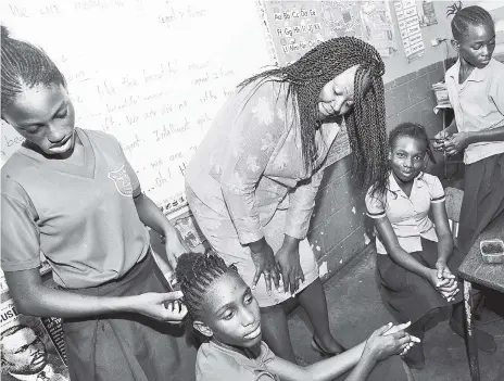  ?? FILE ?? Principal Beverley Gallimore-Vernon encourages students as they comb each other’s hair at Maxfield Park Primary School’s Girls’ Day on May 26. Hairstyles and uniform lengths have been flash points for school discipline, with school administra­tors and...