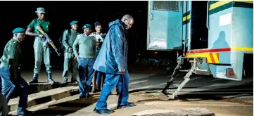  ??  ?? Biti, surrounded by police officers, walks past a prison vehicle as he was given bail at the Harare Magistrate­s Court after being taken handcuffed to face charges of public violence as well as the illegal declaratio­n of election results. — AFP photo