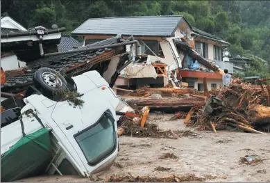  ?? KYODO VIA REUTERS ?? Houses and a vehicle are damaged by a swollen river after heavy rain hit the area in Asakura, Japan, on Thursday.