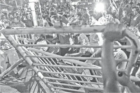  ?? — AFP photo ?? Photo shows supporters of the Bharatiya Janata Party (BJP) facing off with Indian police next to torn down barricades during clashes between rival groups during a campaign rally event held by BJP president Amit Shah in Kolkata.