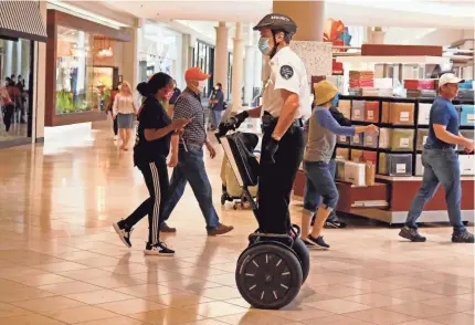  ?? SUE OGROCKI/ AP ?? A security guard wears a mask while patrolling on a Segway inside Penn Square Mall in Oklahoma City in May.