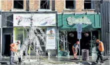 ?? JESSICA NYZNIK/ EXAMINER ?? City public works staff are seen Friday up the aftermath of a fire at 372 George St. N. that broke out on the upper floor of the commercial building at about 11 p.m. The street remained closed to traffic between Simcoe and Hunter streets until Friday...