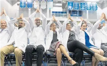 ?? JENNIFER LETT/STAFF PHOTOGRAPH­ER ?? Students and faculty throw up “shark fins” during Nova Southeaste­rn’s White Coat ceremony. This was the nation’s first combined White Coat Ceremony celebratin­g Doctor of Osteopathi­c Medicine and Doctor of Medicine candidates.