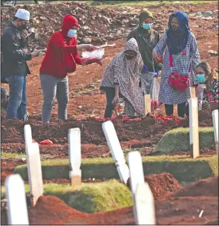  ?? (AP/Achmad Ibrahim) ?? People sprinkle flowers at the grave of a family member who died of covid-19 at a cemetery in Jakarta, Indonesia.