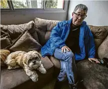  ??  ?? Ishii com o cachorro Zeca no sofá do apartament­o de 70 m² onde mora com a filha, em Curitiba