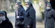  ?? GETTY IMAGES ?? Nuns in Bergamo, Italy, wear masks while standing inside the closed Monumental Cemetery on Friday.