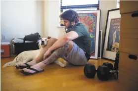  ?? Amy Osborne / Special to The Chronicle ?? Kieran Blubaugh pets Julia as he takes a break from packing his apartment on San Francisco’s Russian Hill in preparatio­n for his move to Dallas.