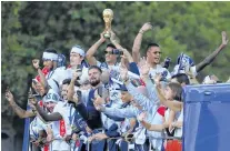  ?? AP PHOTO ?? France’s Raphael Varane holds the trophy as he celebrates with teammates on the roof of a bus while parading down the Champs-elysee avenue in Paris, in Paris, Monday.