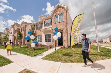  ?? Brett Coomer/Staff photograph­er ?? Wan Bridge Group CEO Tung Qiao walks past townhomes that are ready to lease in the Clearwater at Balmoral subdivisio­n.