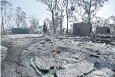  ?? EPA ?? A resident inspects the remnants of his burnt water tanks after bushfires swept through the area the day before in Mount Larcom, Queensland yesterday.