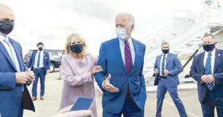  ?? AP ?? File photo shows US President-elect Joe Biden being moved back by soonto-be first lady Jill Biden from members of the media as he speaks outside his campaign plane at the airport in New Castle, Delaware to travel to Miami for campaign events.