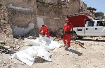  ??  ?? Iraqi civil defence cover a body in the northern Iraqi city of Mosul. — AFP photo