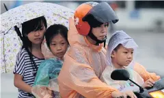  ?? PATIPAT JANTHONG ?? A woman and her children ride on a motorcycle during a heavy downpour in Sa Kaeo’s Aranyaprat­het district.