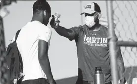  ??  ?? Trainer Joey Pena, right, uses a thermomete­r on the forehead of sophomore running back Gervawn Neville for a temperatur­e check Thursday in Arlington, Texas.