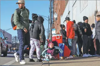  ?? ARMANDO L. SANCHEZ VIA NEWSCOM ?? Three-year-old Yanis Vasques (center) sits next to her mother who sells food outside a migrant shelter on the Lower West Side in Chicago on Feb 15.