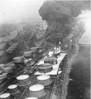  ??  ?? Left, a later aerial photo shows the burning tanks being surrounded with a wall of fire-retardant foam, while neighbouri­ng tanks to the left of the picture are being sprayed with water to keep them cool