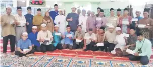  ??  ?? SUMBANGAN IKHLAS: Dr Hazland (berdiri tengah) merakam kenangan bersama barisan penerima sumbangan kebajikan dari Kampung Bako Hilir dan Bako Hulu Kuching baru-baru ini.