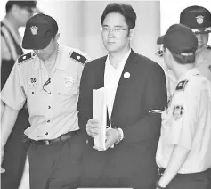  ??  ?? Jae-Yong (centre) escorted by prison guards as he arrives at the Seoul Central District Court in Seoul. — AFP photo