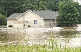  ?? SALLY CARROLL/MCDONALD COUNTY PRESS ?? A woman watching the floodwater­s flowing on Sunday afternoon said her friends owned this house and had been anticipati­ng selling it before the banks of Indian Creek in Anderson flooded with raging waters. Heavy rains fell on Sunday morning, causing flooding in the Anderson area.