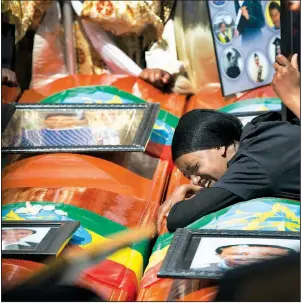  ?? AP/MULUGETA AYENE ?? A woman grieves over empty caskets draped with Ethiopian flags Sunday at a mass funeral at the Holy Trinity Cathedral in Addis Ababa. Thousands of people attended the ceremony held in memory of the victims of last week’s Ethiopian Airlines crash.