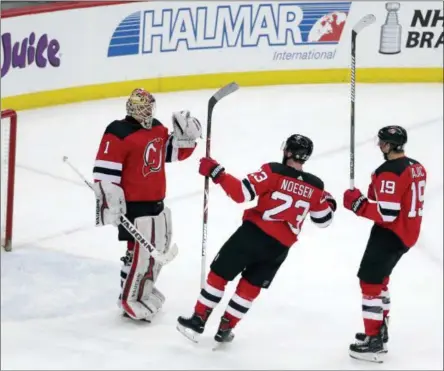  ?? JULIO CORTEZ - THE ASSOCIATED PRESS ?? New Jersey Devils players, from left, former Albany Devils goalie Keith Kinkaid (1), Stefan Noesen (23) and former Albany River Rats center Travis Zajac (19) celebrate after a win.