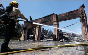  ?? ?? A US firefighte­r works to put out hotspots at one of more than 20 homes destroyed by the Coastal fire in Laguna Niguel, California