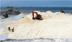  ?? — AP ?? False front: A file photo showing workers spreading artificial sand at Manila Bay.