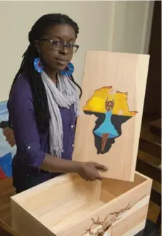  ?? MIKE GROLL PHOTOS/THE ASSOCIATED PRESS ?? Danielle Charlestin shows a burial container she painted that will hold the remains of a slave found in an unmarked grave.