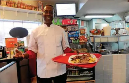  ?? TANIA BARRICKLO—DAILY FREEMAN ?? Albert “Sammy” Bartley, owner of Top Taste Restaurant in Midtown Kingston, serves up a plate of traditiona­l Jamaican food.