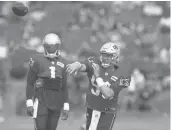  ??  ?? Patriots quarterbac­ks Cam Newton, left, stands nearby as Mac Jones passes the ball during practice Tuesday in Foxborough, Mass.