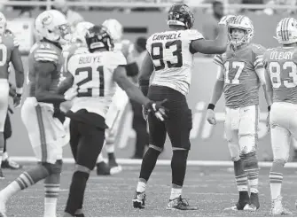  ?? MICHAEL LAUGHLIN/SUN SENTINEL ?? The Jaguars’ Calais Campbell pats the Dolphins’ Ryan Tannehill on the helmet after the QB threw an intercepti­on.